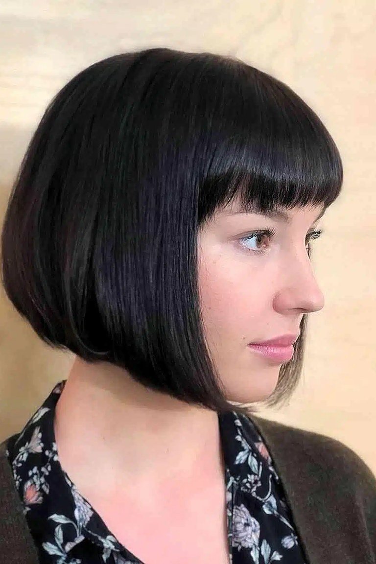 Soft blunt jaw length bob with parted curtain bangs framing the face