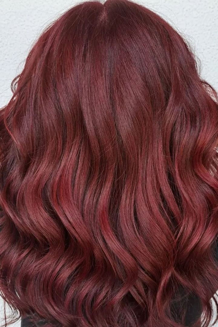Wavy mulled wine burgundy hair with warm cinnamon tones