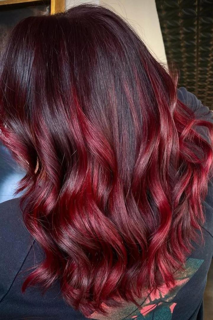 Lived-in burgundy hair with dark roots and soft grown-out colour