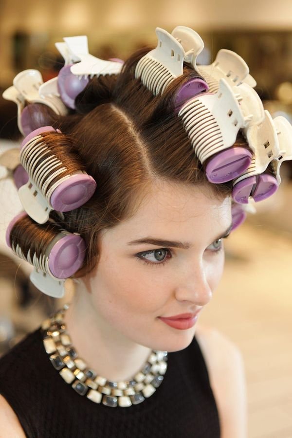 Woman setting her hair in large velcro rollers for a bouncy 90s blowout