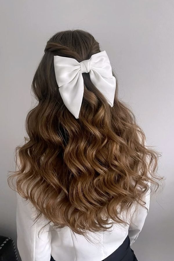 Oversized white bow clip on loose brown waves