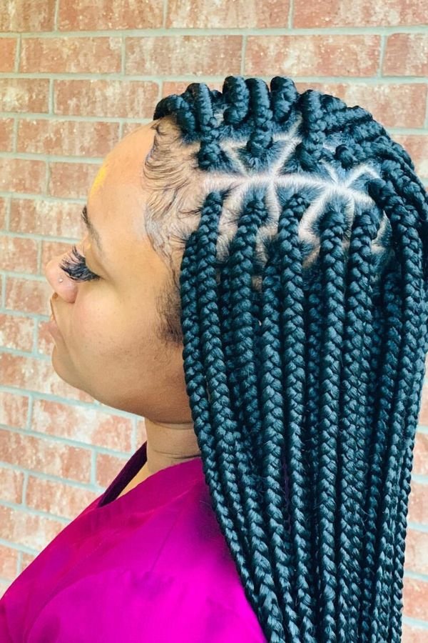 Teal box braids in profile against a brick wall, bold blue-green color