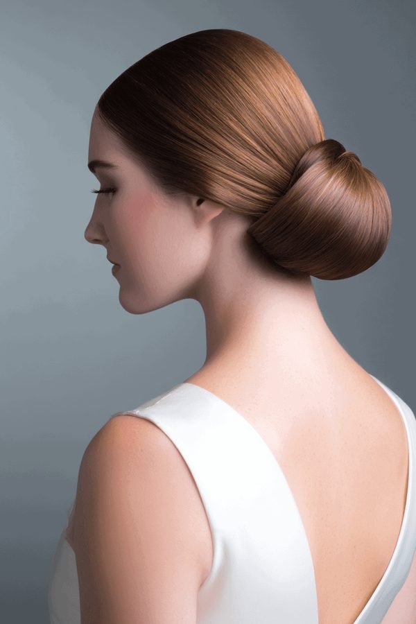 Sleek low bun hairstyle with a smooth polished finish, side view