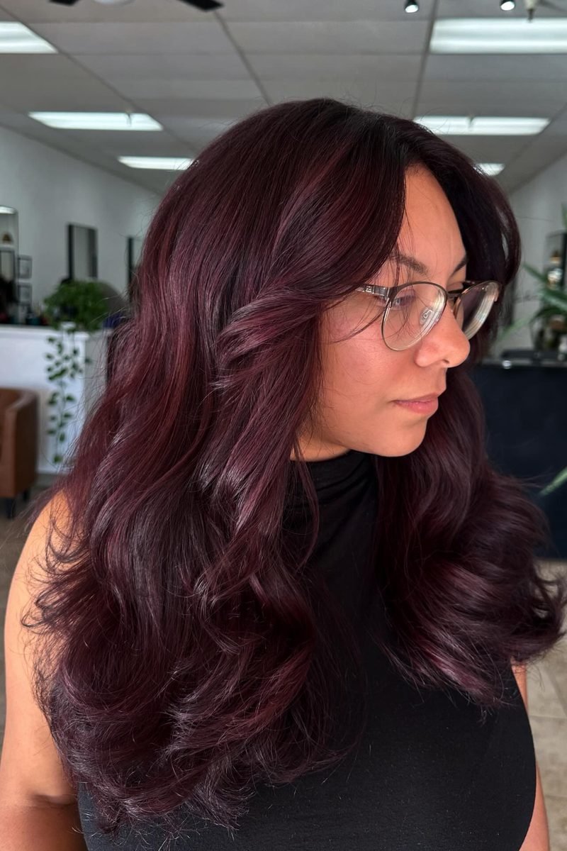 Cherry cola balayage ribbons through dark hair