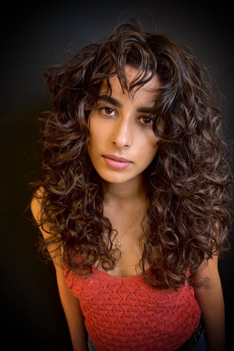 Long dark-brown curly wolf cut with shaggy curtain fringe, front view