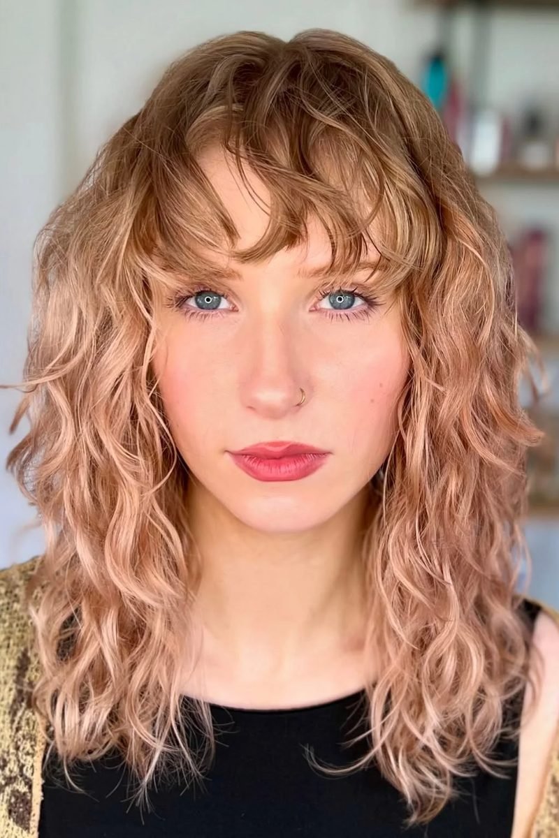 Sandy-blonde curly wolf cut with airy fringe, front view