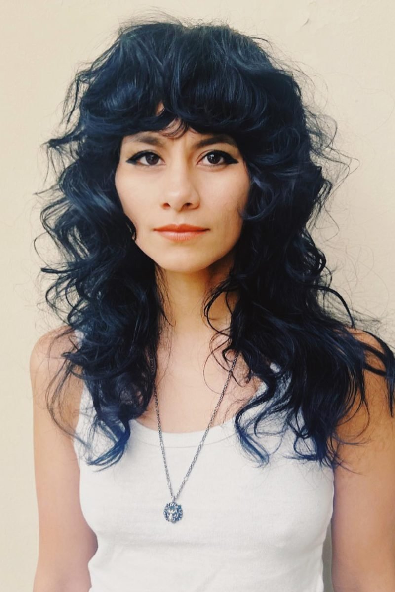 Midnight-blue curly wolf cut with voluminous bangs, front view