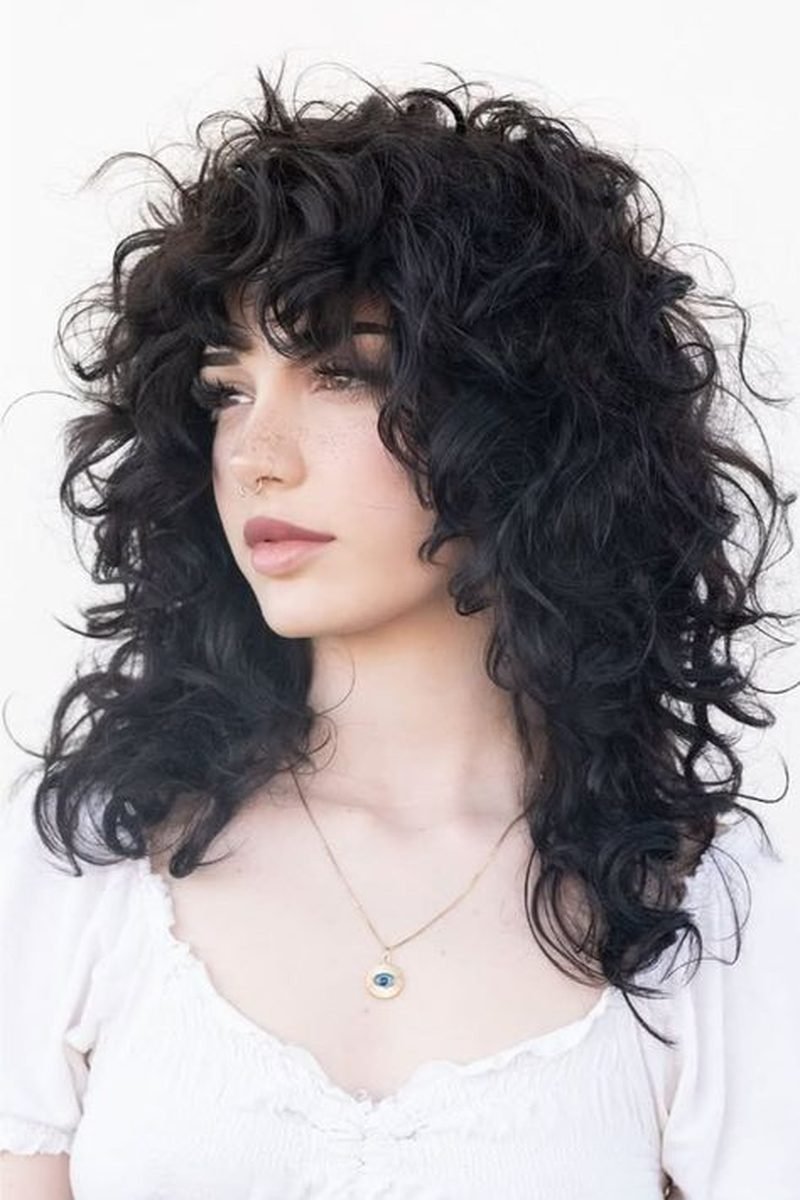 Medium black curly wolf cut with bangs, three-quarter front view