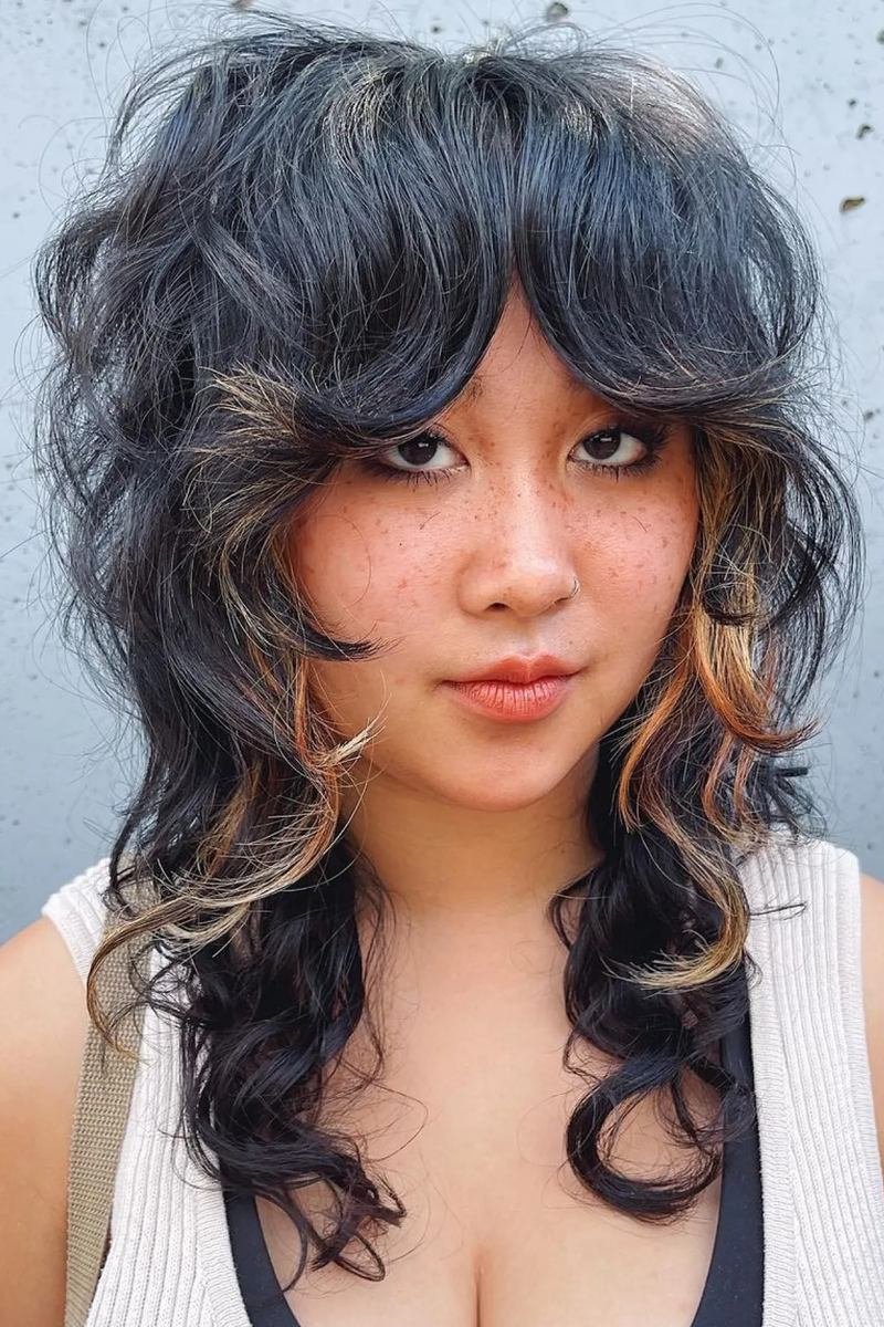 Dark curly wolf cut with blonde money-piece highlights, front view