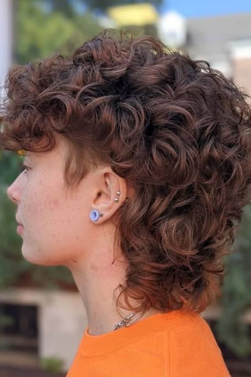 Brown curly wolf cut outdoors, side profile