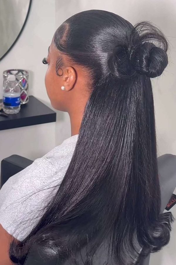 Sleek straight half-up hairstyle with a sculpted top bun, side profile