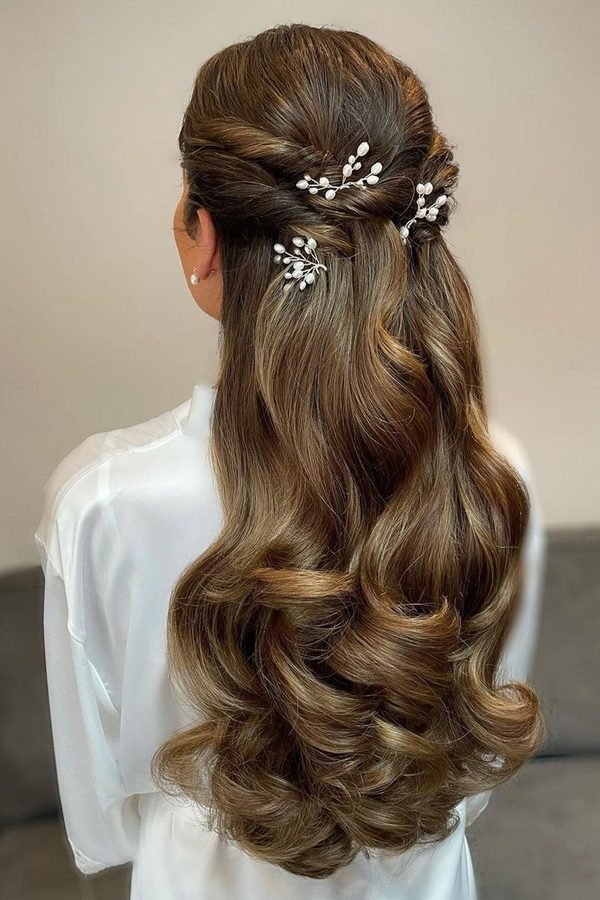 Half-up hairstyle decorated with pearl hair pins and big soft curls, back view