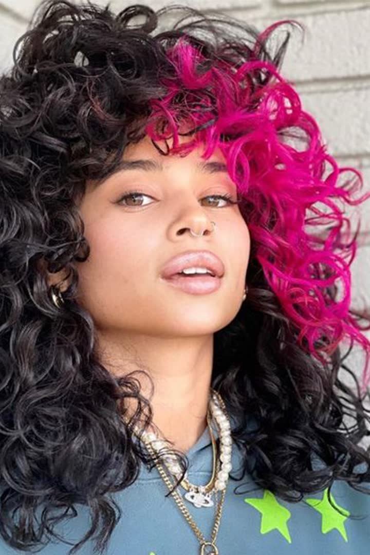 Pink face-framing streak on curly hair