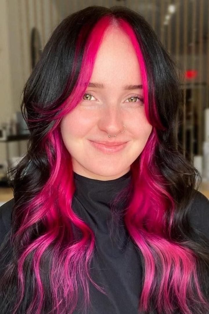Bold magenta face-framing peekaboo sections on dark hair