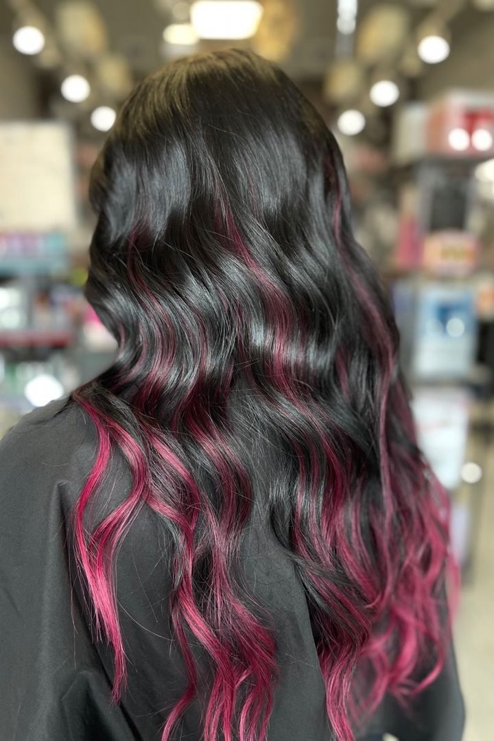 Deep magenta peekaboo streaks on black wavy hair