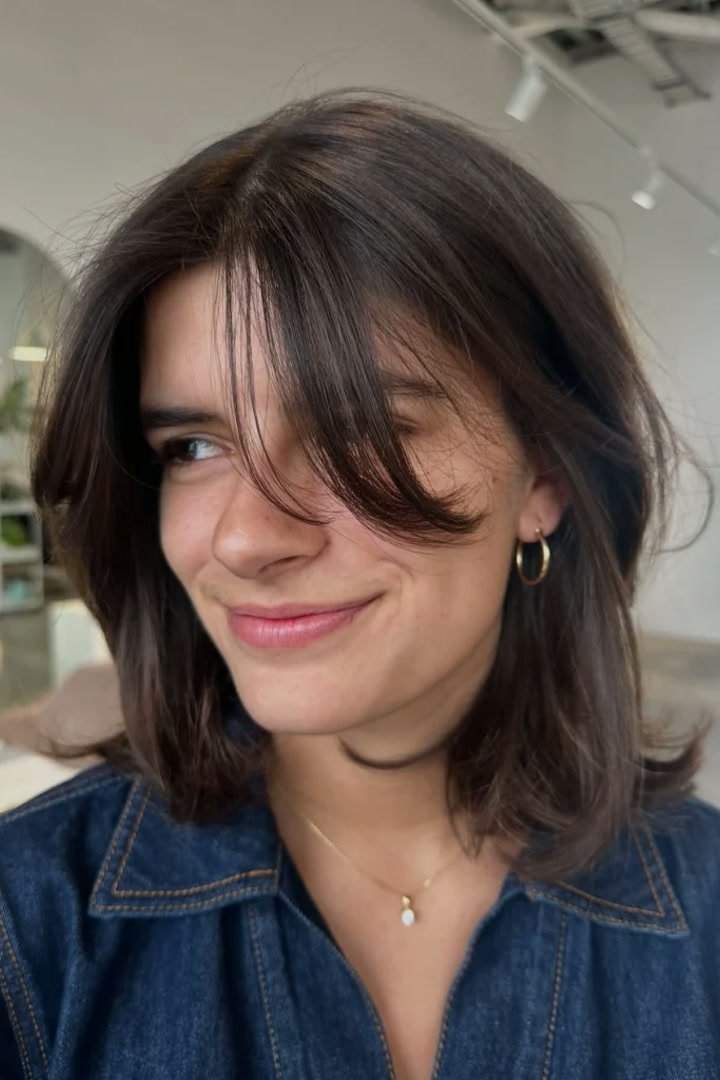 Kitty cut with side-swept bangs blending into layers