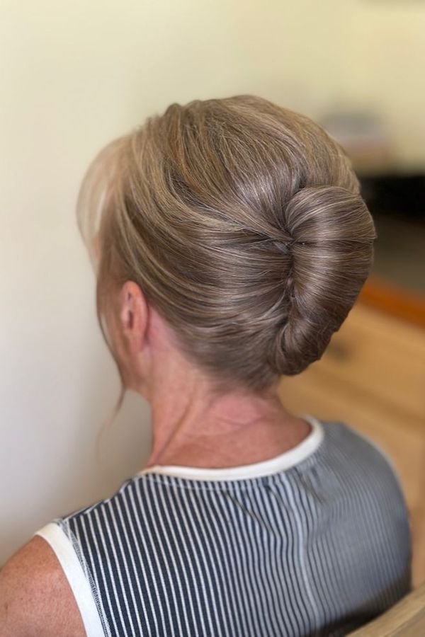 Sleek center-part low bun, back view on an older woman
