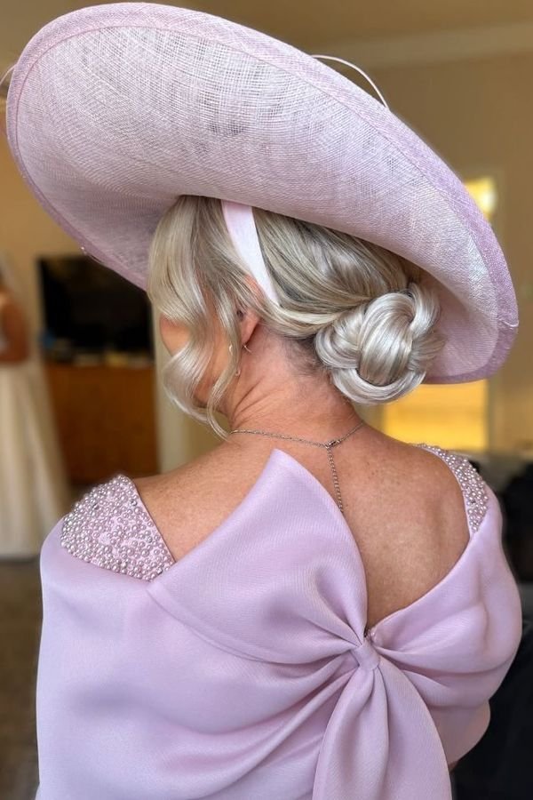 Smooth low bun under a wide lilac wedding hat, back view