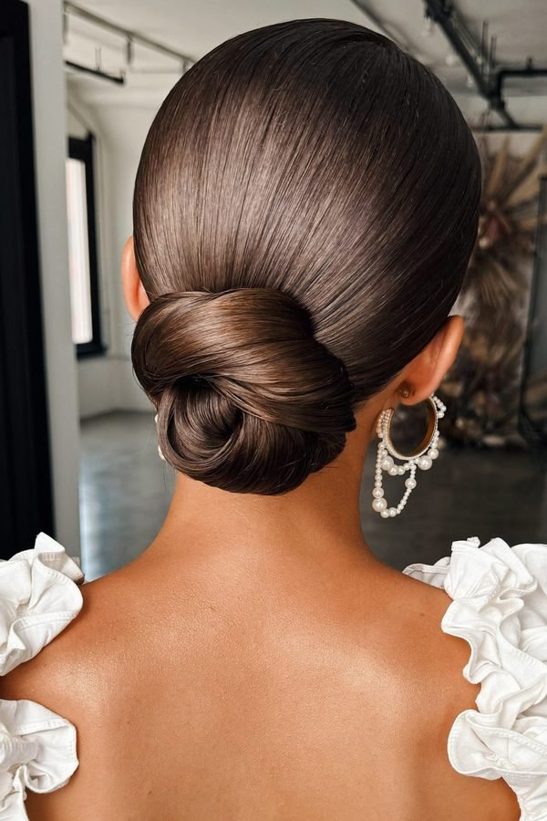 Sleek low bun with silver glitter along the parting for NYE