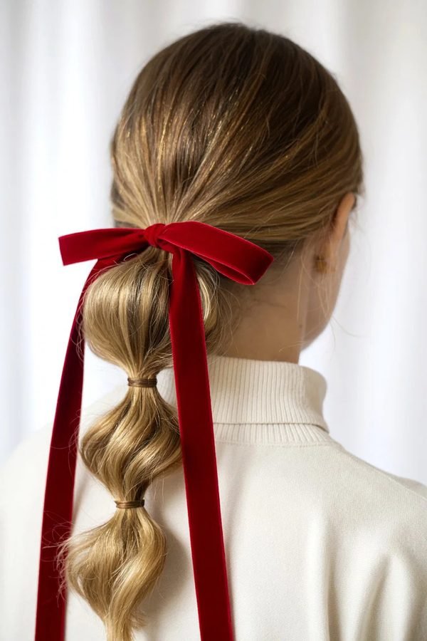 Low bubble ponytail tied with a long red velvet ribbon