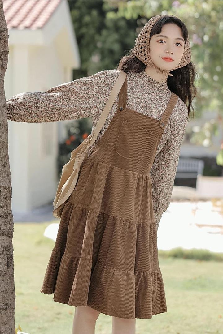 Brown corduroy tiered pinafore dress over a floral blouse with a crochet headscarf