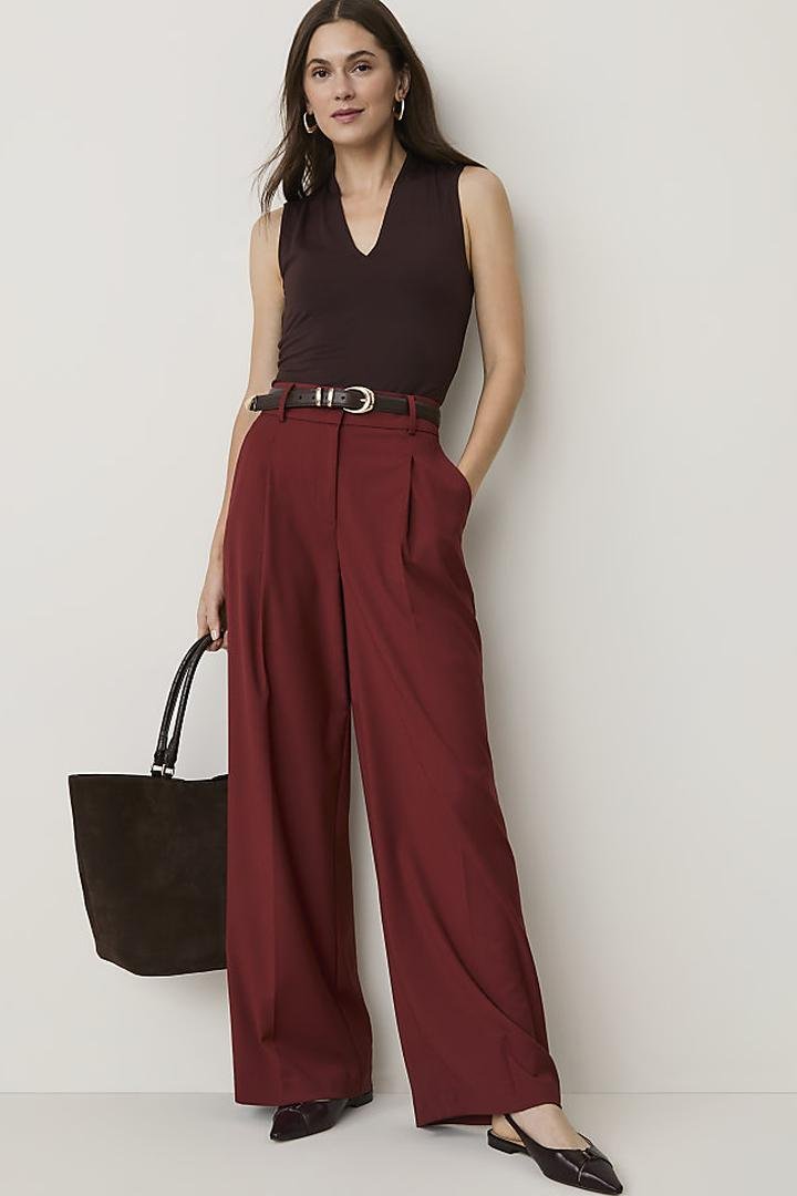 Burgundy high-waisted wide-leg trousers with a dark sleeveless knit top and belt