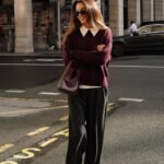 Thanksgiving outfits women will love: woman in a burgundy knit sweater and black wide-leg trousers, fall street style