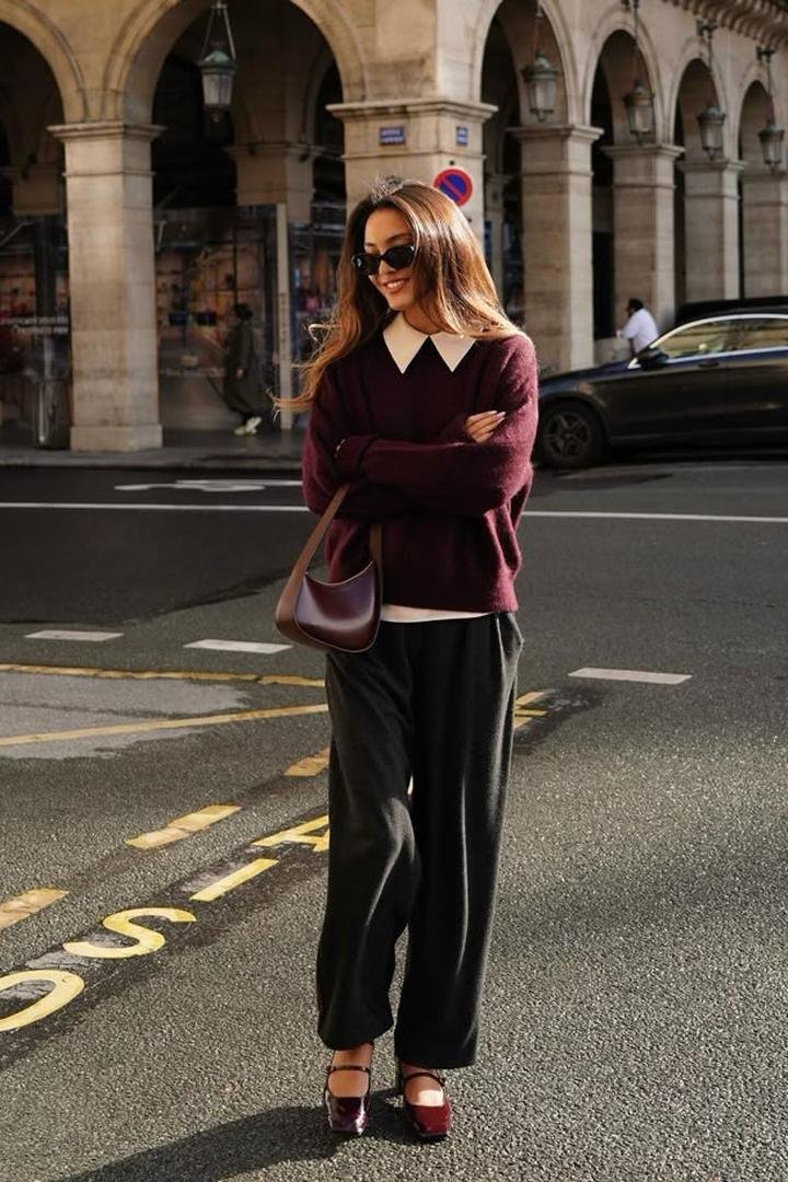 Thanksgiving outfits women will love: woman in a burgundy knit sweater and black wide-leg trousers, fall street style