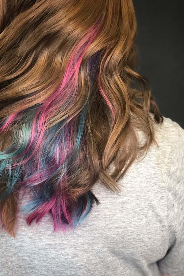 Hidden pink and teal peekaboo streaks under dark hair