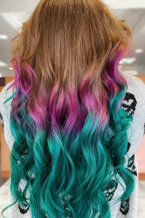 Natural brown roots fading to pink and teal ombre ends