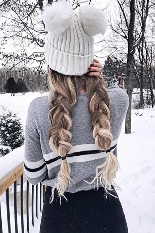Double Dutch braids under a white pompom beanie, back view