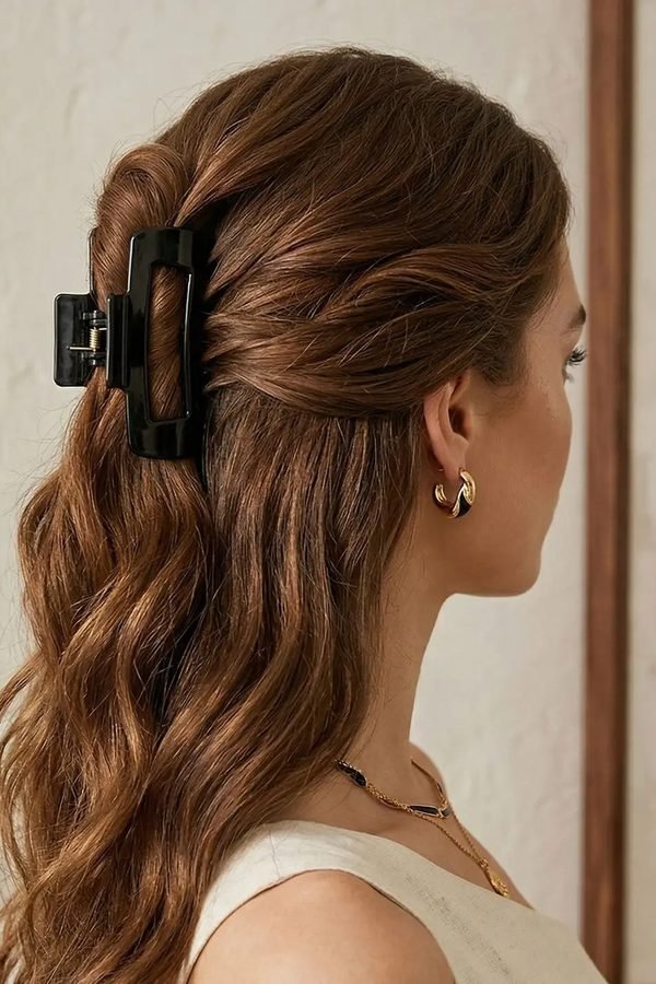 Half-up hairstyle secured with a black claw clip, back view
